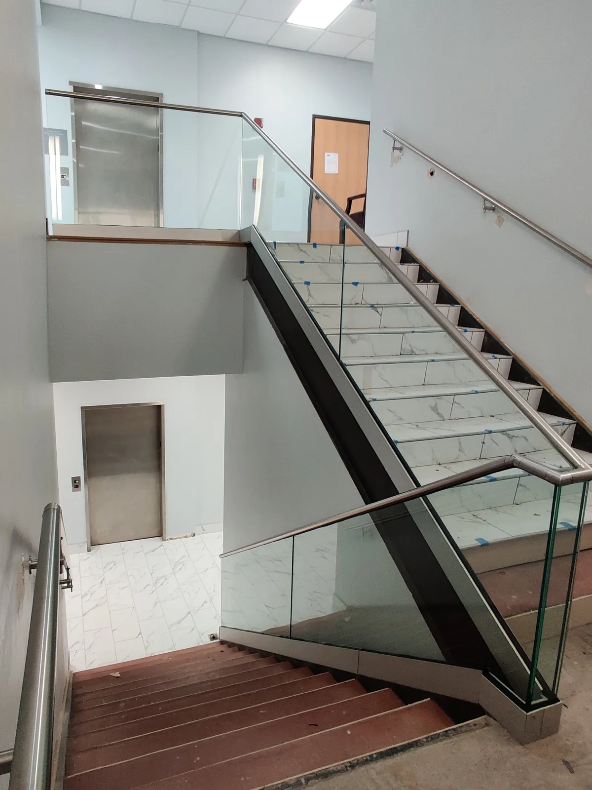 Glass stair railing with stainless handrails in a commercial stairwell