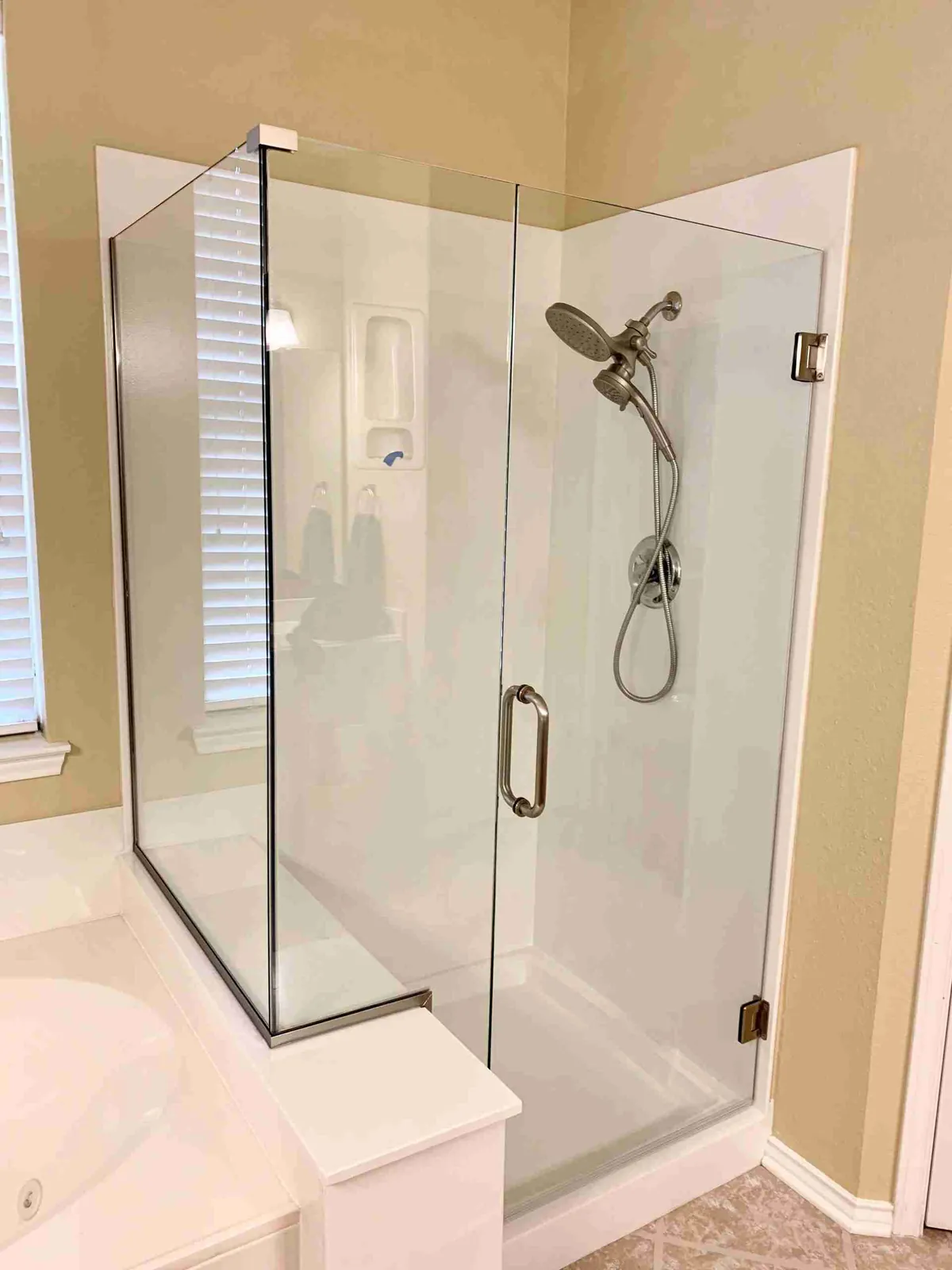 Frameless corner shower with a glass door and brushed nickel hinges and pull