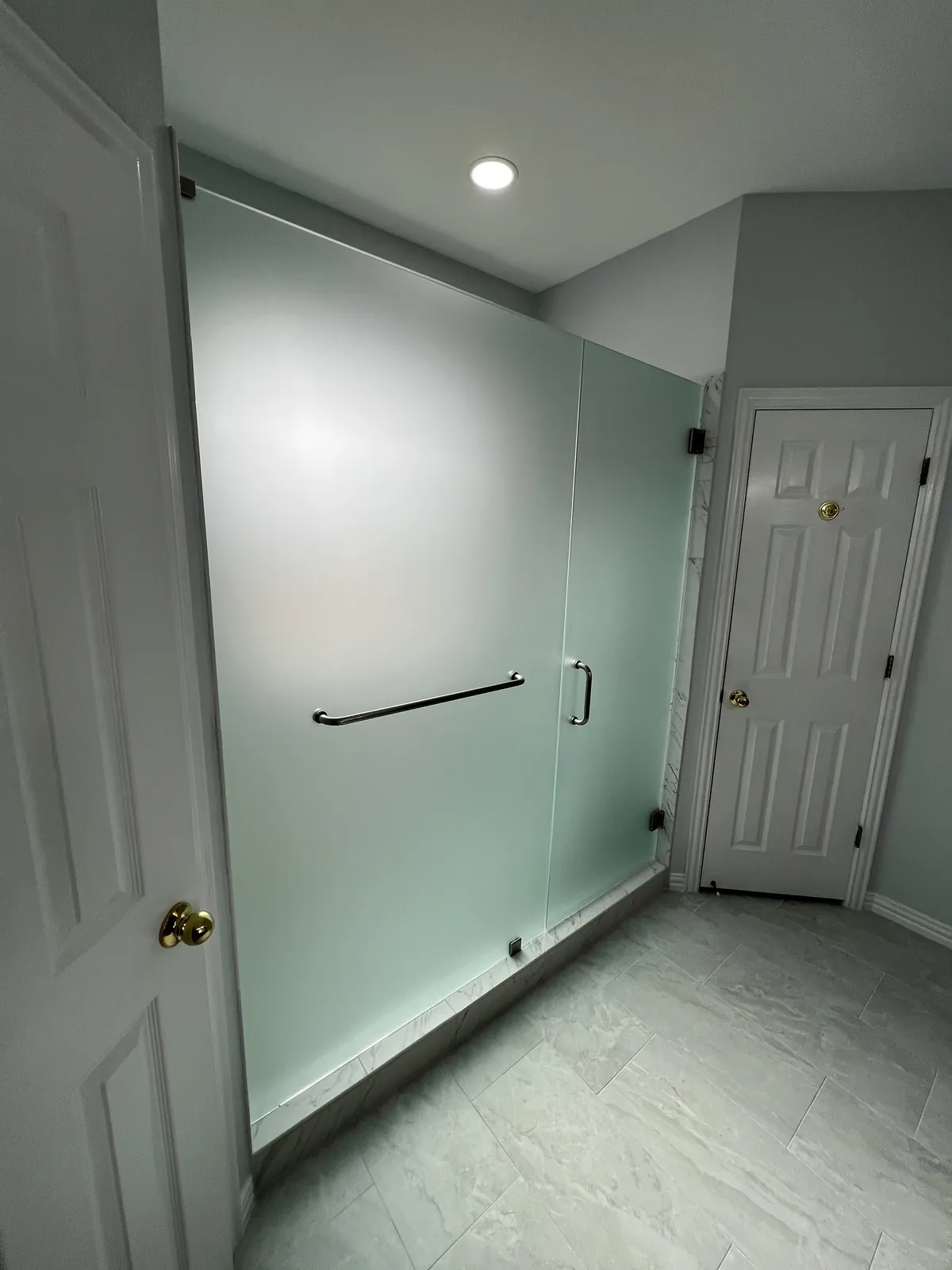 Frosted glass shower door and panel with a chrome towel bar