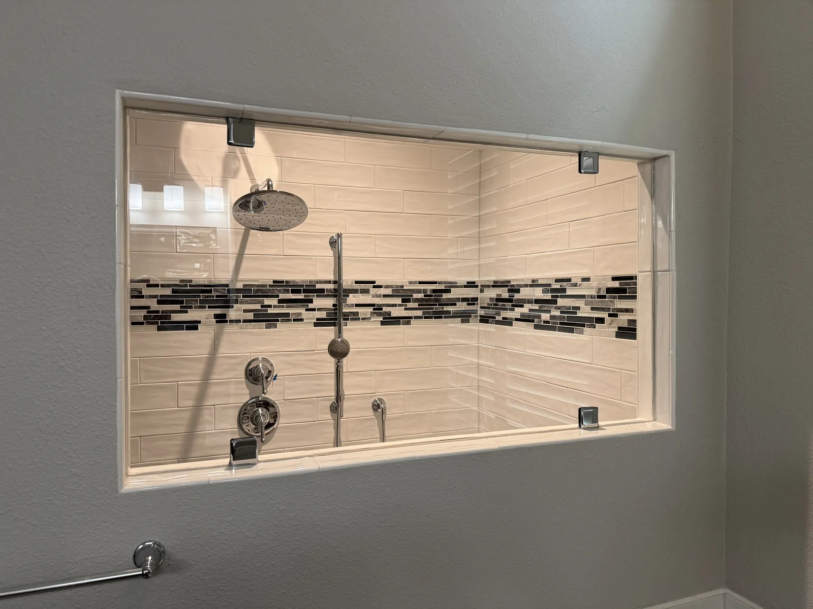 Fixed glass panel set into a wall opening, looking into a tiled shower