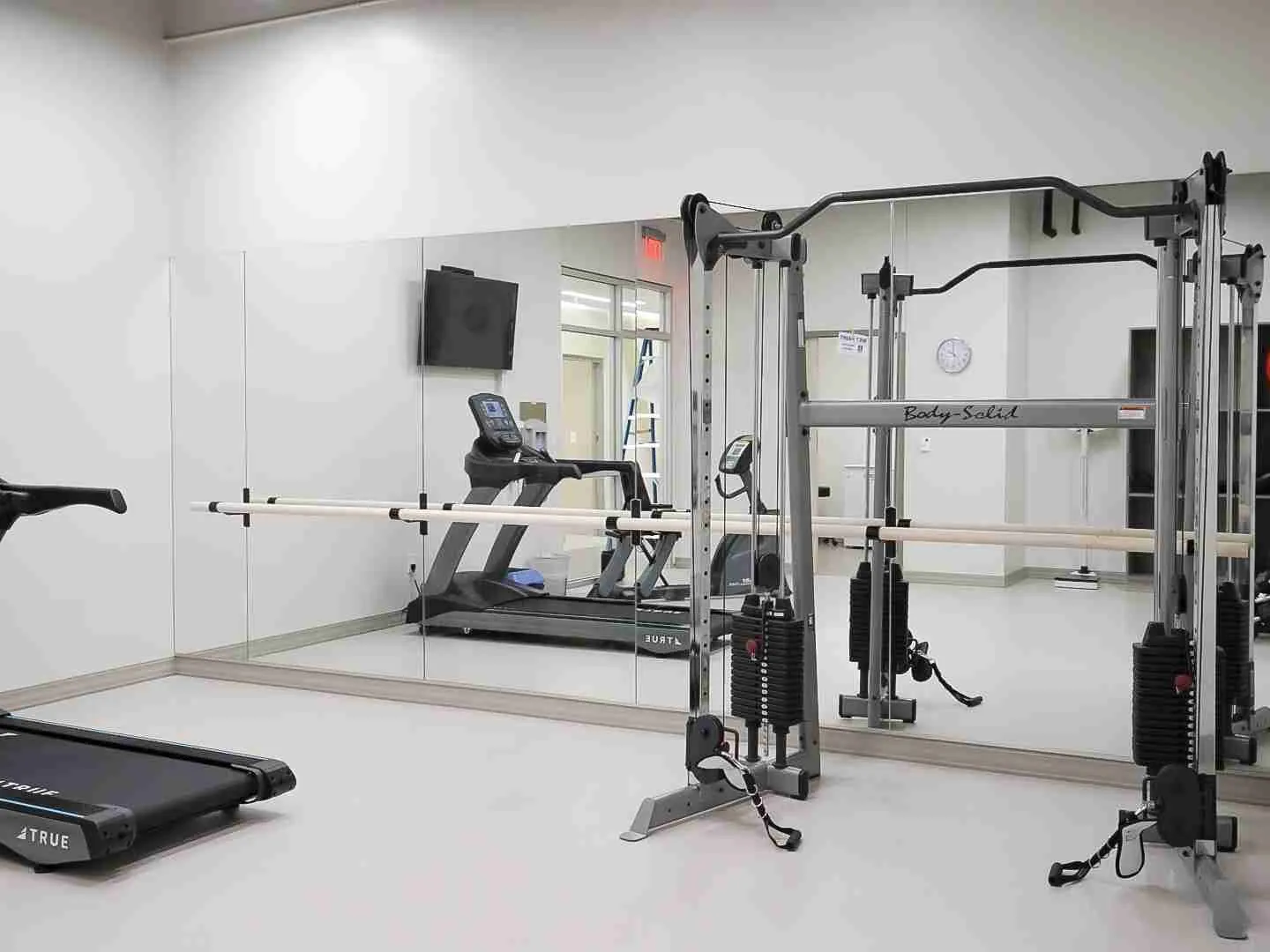 Wall mirror behind home gym equipment and a ballet barre