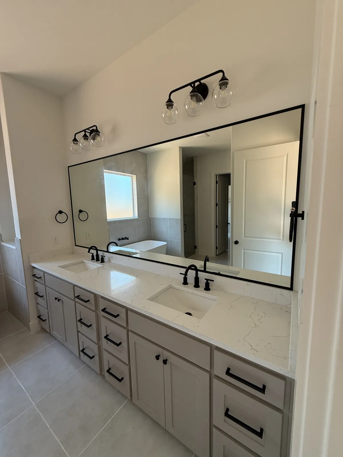 Wide black-framed mirror above a double bathroom vanity