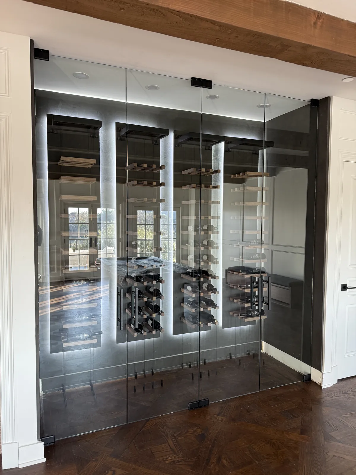 Glass wine room with black hardware and illuminated bottle racks