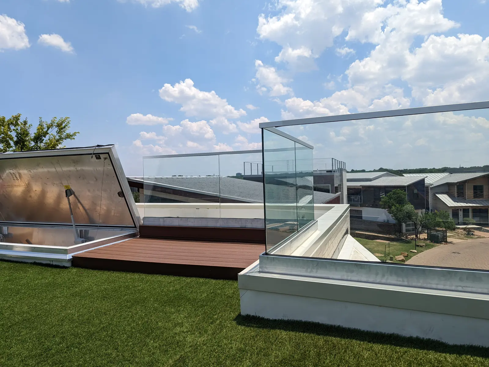 Frameless glass railing around a rooftop terrace with artificial turf