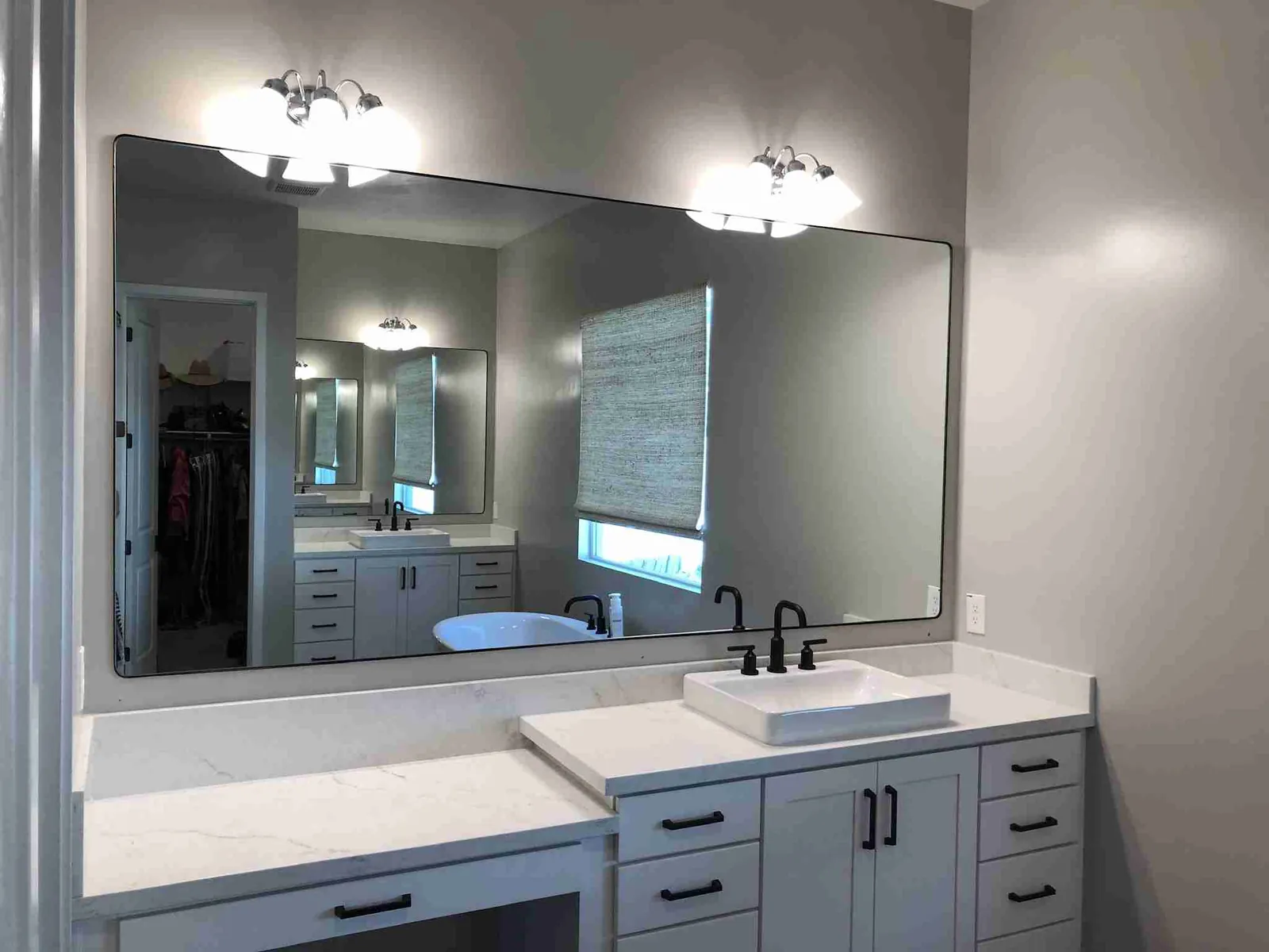 Wide black-framed mirror with rounded corners above a vanity with a vessel sink