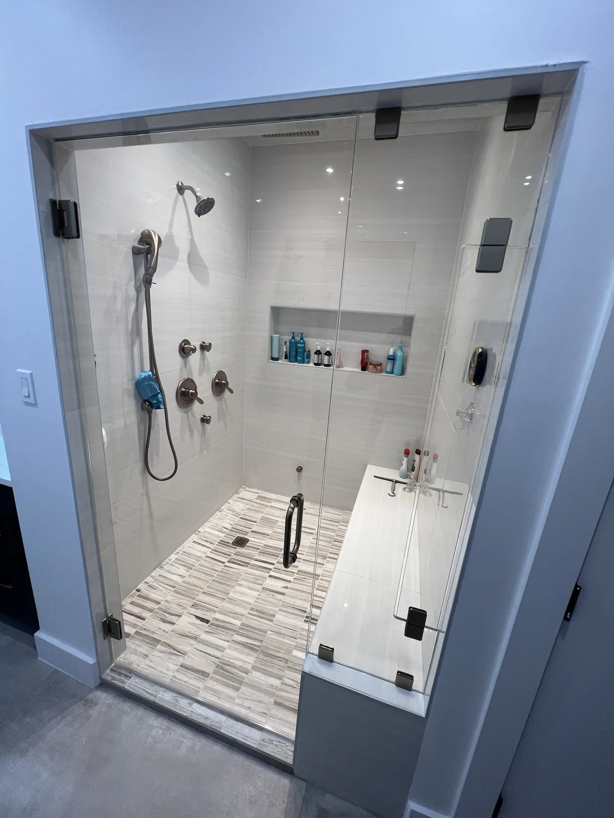 Glass steam shower enclosure with a transom panel and a tiled bench inside